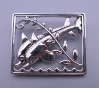 A silver brooch formed as dolphins. 3.5 cm wide.