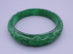 An apple green jade carved bangle. 7.5 cm diameter.