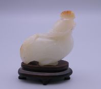 A Chinese carved jade model of a chicken eating corn on a wooden stand. 4.5 cm high.