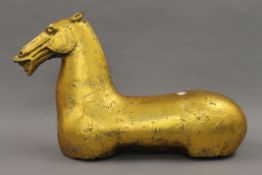 A golden coloured model of a horse. 31 cm high.