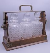 An oak plate mounted three bottle decanter tantalus with label for Goldsmiths & Silversmiths