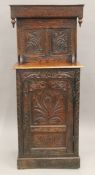 A 19th century carved oak single drawer cupboard. 63 cm wide.