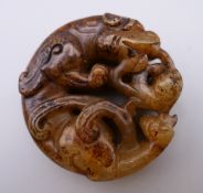 A jade roundel formed as a dragon. 4.75 cm diameter.