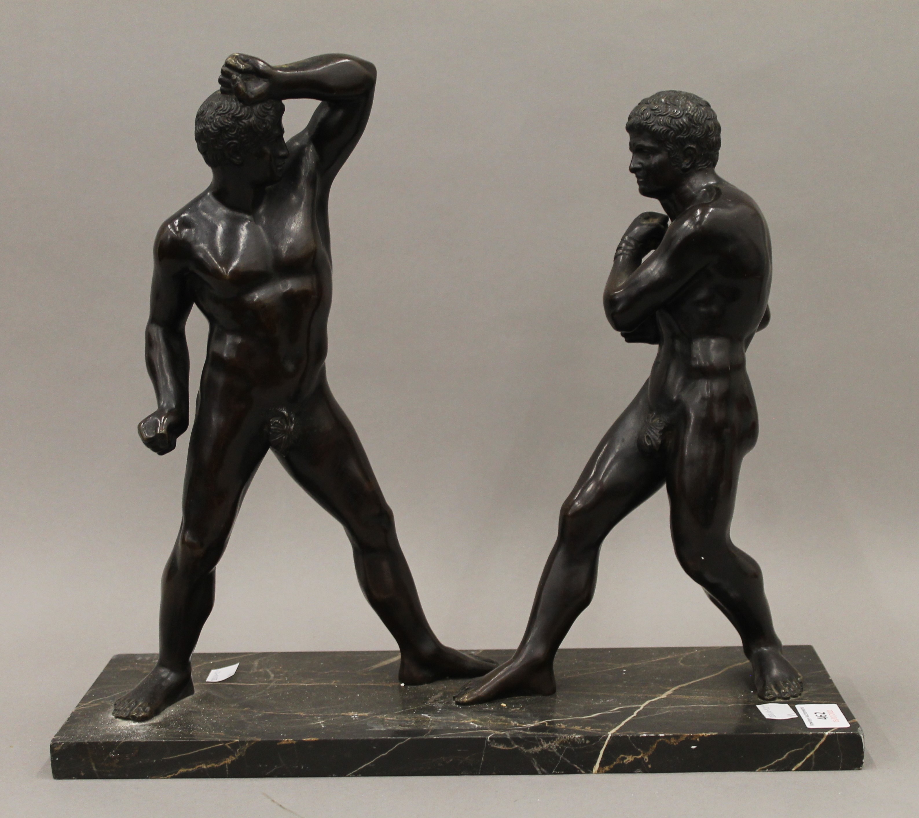 A pair of patinated bronze models of gladiators mounted on a marble plinth base. 40 cm long.