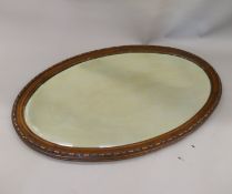 A large Edwardian oval wood framed mirror. 98 cm wide.