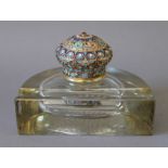 A glass inkwell set with an enamel decorated silver gilt lid, bearing Russian marks. 15.5 cm wide.