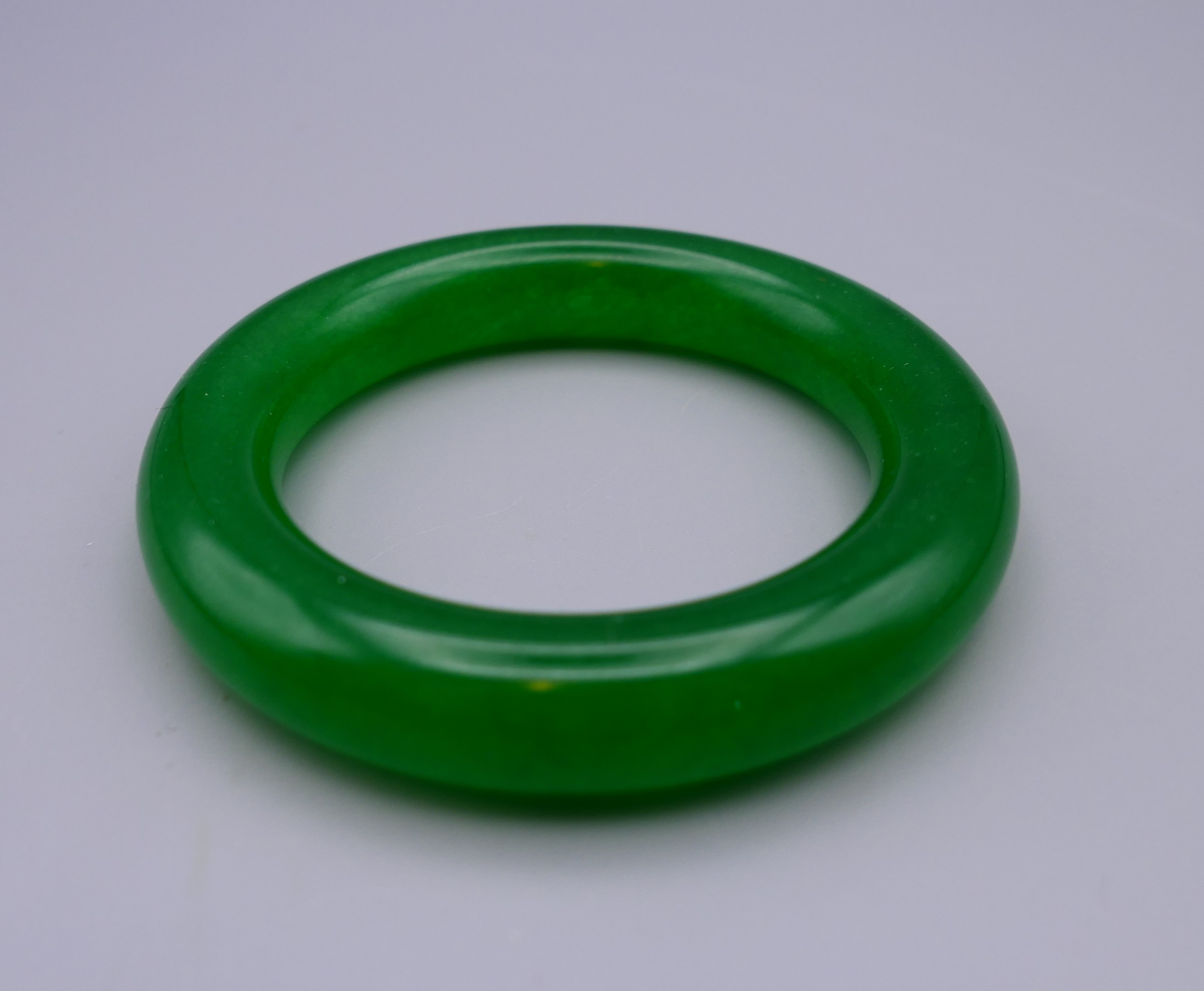 An apple green jade bangle. 8.5 cm diameter. - Image 2 of 3