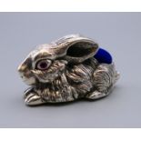 A silver rabbit form pin cushion. 5 cm long.