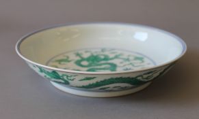 A Chinese porcelain dish decorated with green dragons. 22 cm diameter.