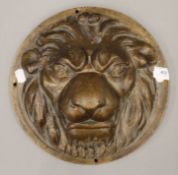 A Victorian patinated cast metal plaque depicting a lion mask. 30 cm diameter.