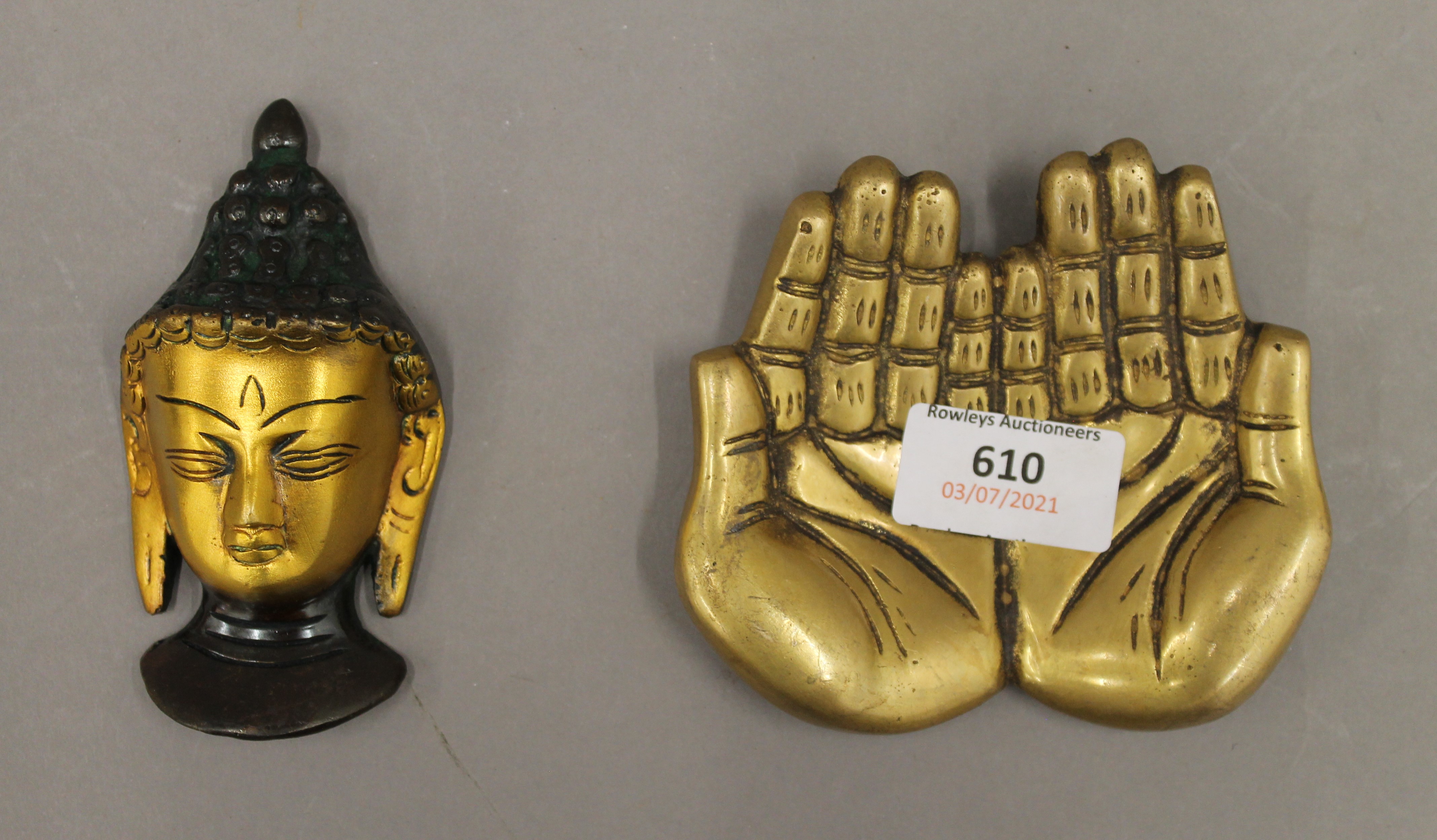 A bronze hand and Buddha head. The former 11 cm wide.