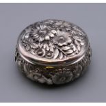 A sterling silver circular embossed pill box. 5.5 cm diameter.