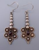 A pair of silver and garnet earrings. 5 cm high.