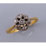 An 18 ct gold and diamond flower head ring. Ring size M. 8 mm high.