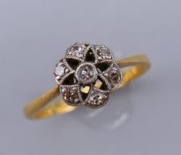 An 18 ct gold and diamond flower head ring. Ring size M. 8 mm high.