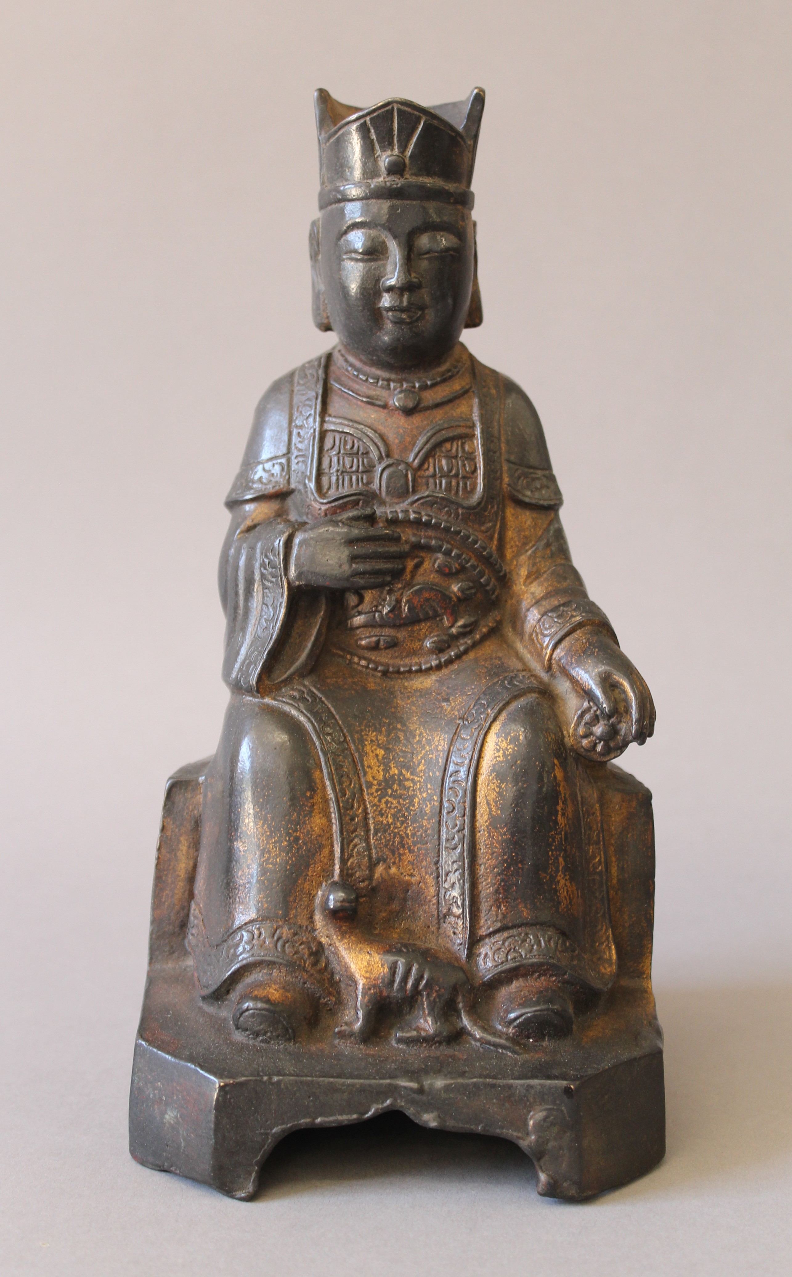 A bronze model of a seated deity. 23 cm high.