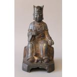 A bronze model of a seated deity. 23 cm high.