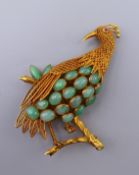 An 18 ct gold jade bird brooch. 6.5 cm high. 15.3 grammes total weight.