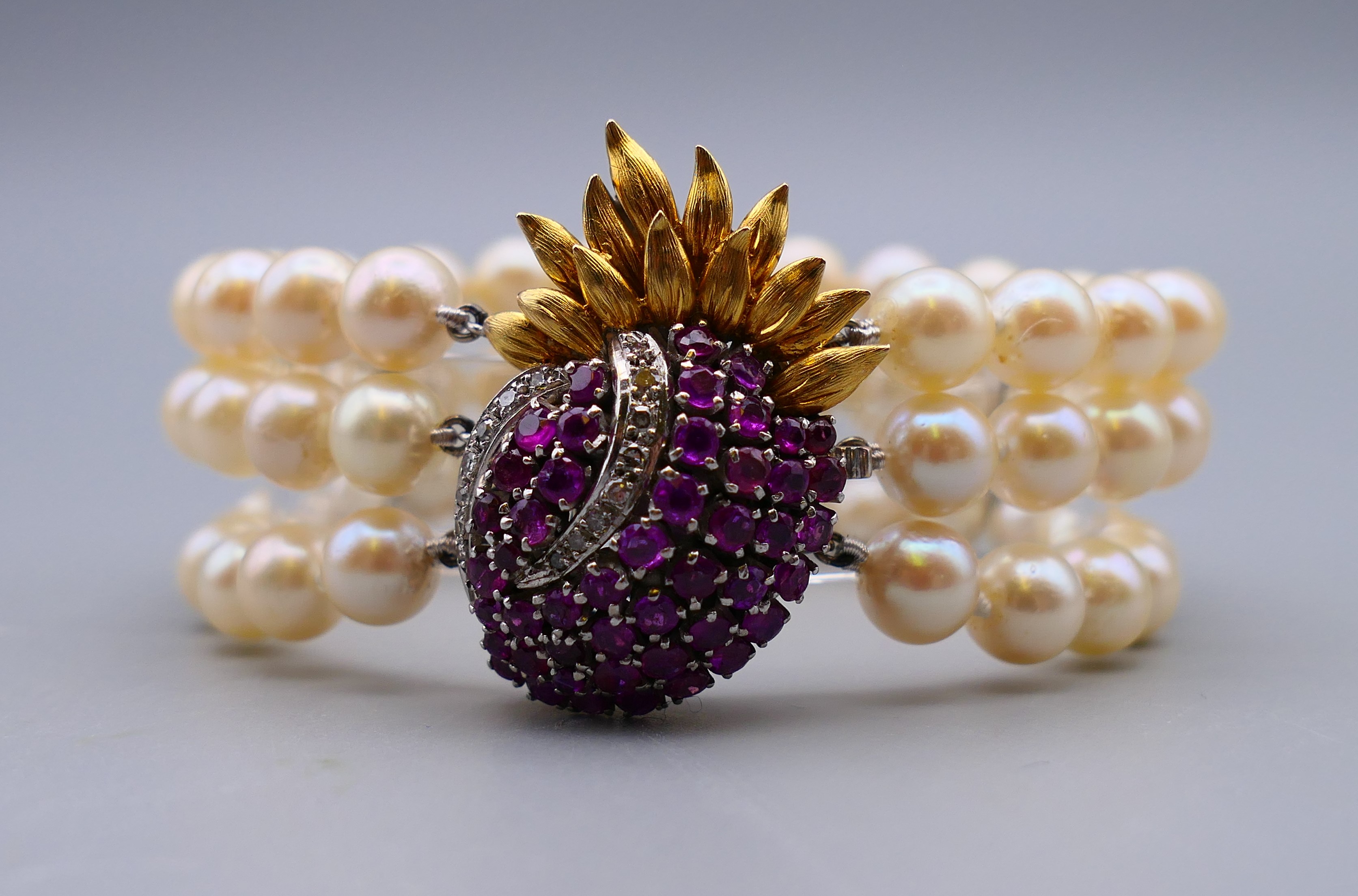 A three strand pearl bracelet, with ruby and diamond set 14 K gold clasp. 18 cm long.