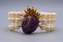 A three strand pearl bracelet, with ruby and diamond set 14 K gold clasp. 18 cm long.