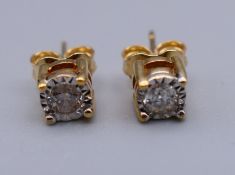 A pair of 9 ct gold diamond solitaire earrings. 5 mm diameter.