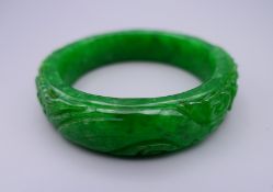 A carved apple green jade bangle. 7 cm diameter.