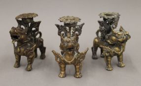 Three antique brass dog-of-fo candle holders. Each approximately 9 cm high.