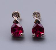 A pair of 9 ct gold diamond and synthetic ruby earrings. 8 mm high.