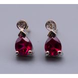 A pair of 9 ct gold diamond and synthetic ruby earrings. 8 mm high.