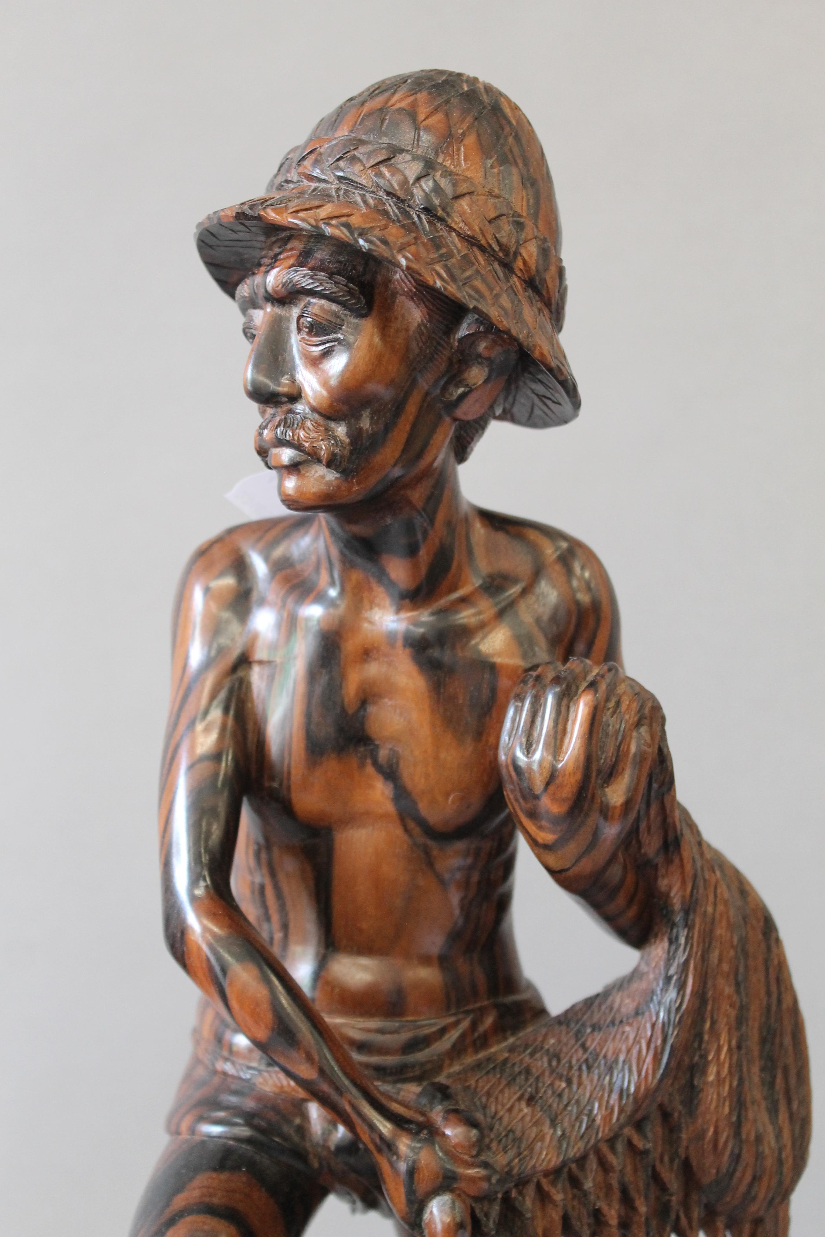 An Eastern carved hardwood fisherman figure. 43 cm high. - Bild 2 aus 5