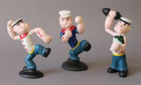 A set of three cast iron Popeye figures. The largest 15.5 cm high.