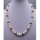 A string pearl and jade bead necklace with a 14 ct gold clasp. 42 cm long.