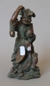 A Chinese patinated bronze model of a man holding coins above a lucky frog. 20 cm high.