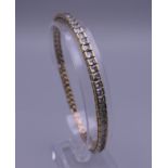 A 9 ct gold tennis bracelet set with white stones. 19.5 cm long. 17.1 grammes total weight.