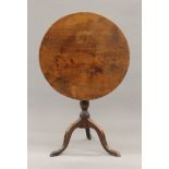 A George III elm topped tilt top tripod table. 68 cm diameter.