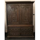 An 18th/19th century carved oak two door side cupboard, the doors carved with knights.