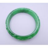 A carved jade bangle. 7.25 cm exterior diameter and 5.75 interior diameter.