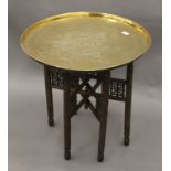 An Eastern folding table with engraved brass tray top, together with an additional base. 62.