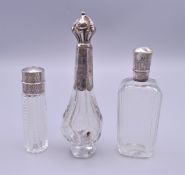 Three silver top scent bottles. The largest 12 cm high.