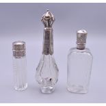 Three silver top scent bottles. The largest 12 cm high.