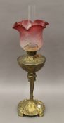 An Art Nouveau style brass lamp with red etched shade. 72 cm high overall.