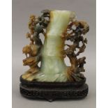 A Chinese carved jade brush pot mounted on a carved wooden stand. 20 cm high overall.