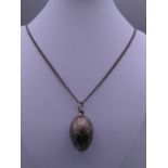 An Edwardian silver egg pendant on chain. The pendant 4 cm high.