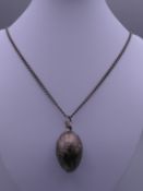 An Edwardian silver egg pendant on chain. The pendant 4 cm high.