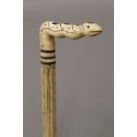 A 19th century carved whalebone walking stick with carved ivory snake form handle. 85.5 cm long.