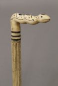 A 19th century carved whalebone walking stick with carved ivory snake form handle. 85.5 cm long.