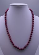 A red pearl bead necklace with a 14 ct gold clasp. 44 cm long.