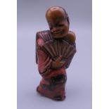 A Japanese carved wooden netsuke formed as a man holding a fan. 5.25 cm high.