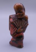 A Japanese carved wooden netsuke formed as a man holding a fan. 5.25 cm high.