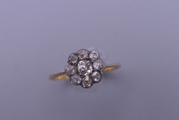 An 18 ct gold and platinum diamond daisy ring. Ring size N. 2.2 grammes total weight.